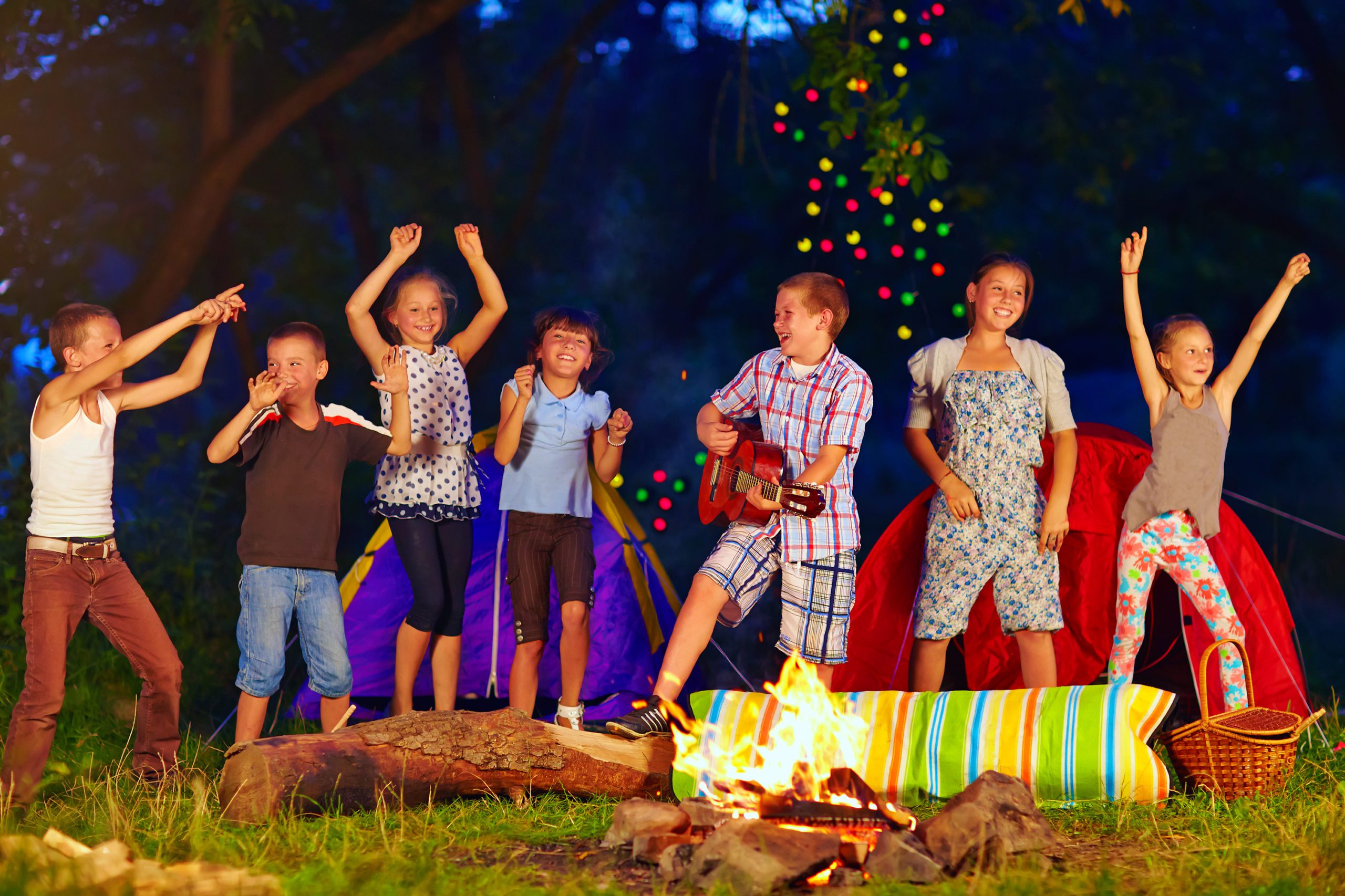 happy kids dancing around campfire